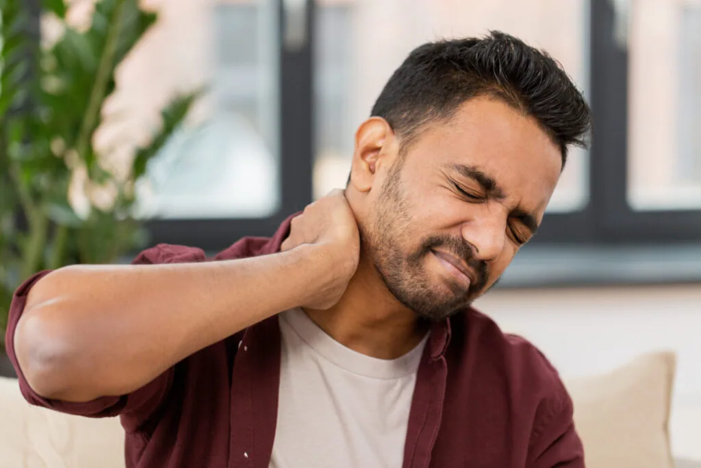 Man touching neck with pained expression, suggesting neck strain or discomfort