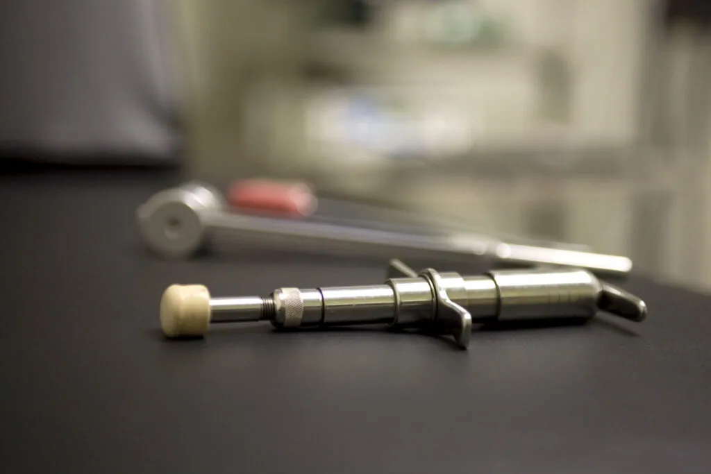 Dental or medical instruments including a metal probe and tool with cream-colored tip on dark surface