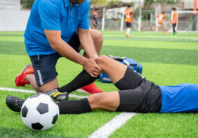 Footballer wearing a blue shirt, black pants injured in the lawn during the race.