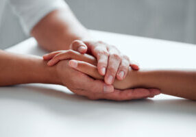 Closeup shot of two unrecognisable people holding hands.